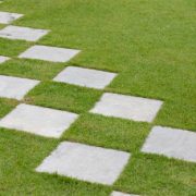 Square stone steps in the garden. concrete walk way path in green turf.