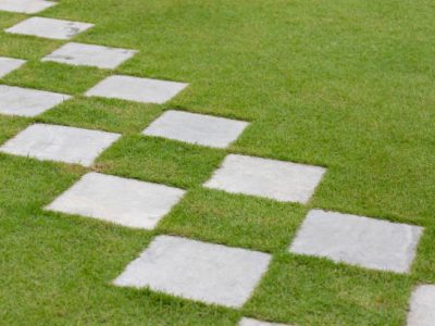 Square stone steps in the garden. concrete walk way path in green turf.