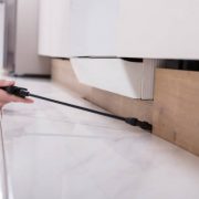 Close-up of a pest control worker's hand spraying pesticide on wooden cabinet