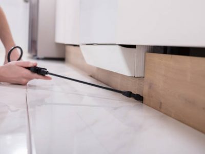 Close-up of a pest control worker's hand spraying pesticide on wooden cabinet