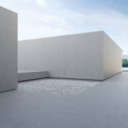 3d rendering of abstract gray building with lake and blue sky background.