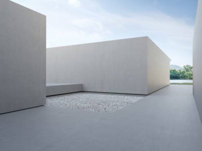 3d rendering of abstract gray building with lake and blue sky background.