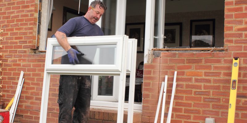 A window fitter removing old windows in preparation for new ones