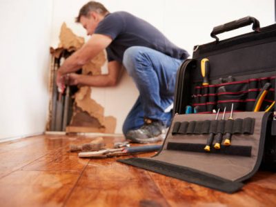 Middle aged man repairing burst pipe,plumbing, focus on foreground