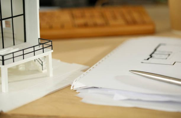 Silver pen lying at working table of architect with blueprints closeup