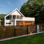 Spacious white house with wooden decoration on garage and wood style fence