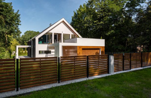 Spacious white house with wooden decoration on garage and wood style fence