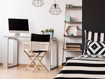 Black and white home interior with bed, pendant lamp, chair, desk and computer