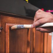 A handyman paints a fresh coat of varnish on the surface of a ba