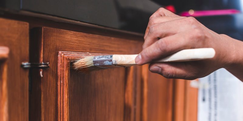 A handyman paints a fresh coat of varnish on the surface of a ba