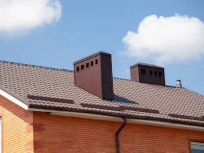 Red metal roof tile and smokestack. modern chimney on brown roof.