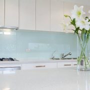Flowers on white kitchen bench with splashback
