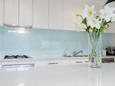 Flowers on white kitchen bench with splashback