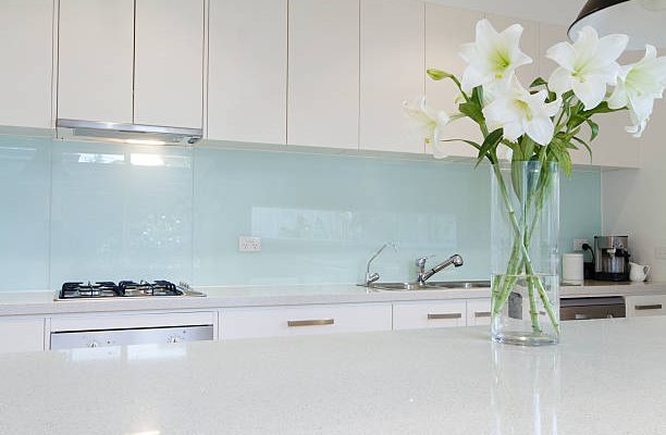 Flowers on white kitchen bench with splashback