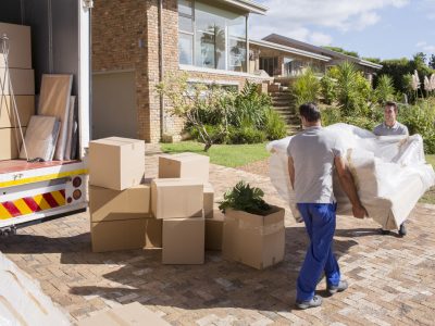 Movers carrying sofa from moving van to house