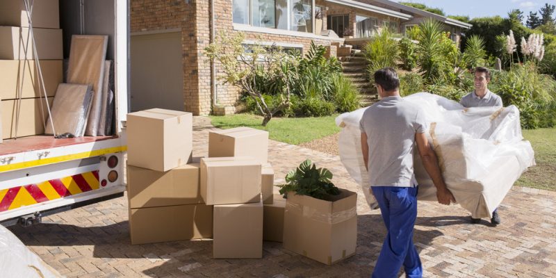 Movers carrying sofa from moving van to house
