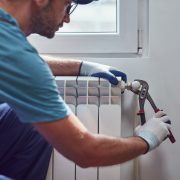 Central heating mechanic and handyman fixing home radiator, gas