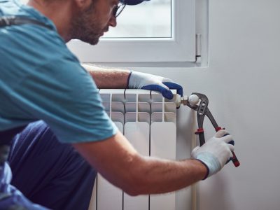 Central heating mechanic and handyman fixing home radiator, gas