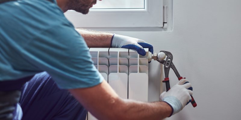 Central heating mechanic and handyman fixing home radiator, gas