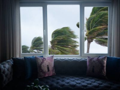 Indoor view of close up window and waving palm trees in windy tropical storm