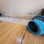 Air mover and a dehumidifier in place to dry a floor after a pipe break.