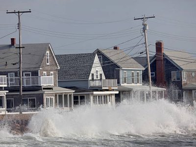 Waves crash against a break wall in conjunction with high tide and a storm.