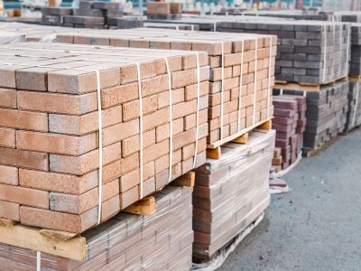 Pallets and packages of freshly produced red bricks in a construction warehouse on the street. concept of repair and building materials