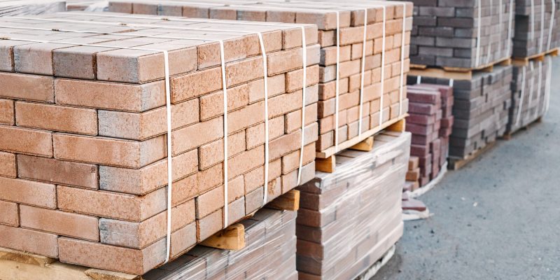 Pallets and packages of freshly produced red bricks in a construction warehouse on the street. concept of repair and building materials