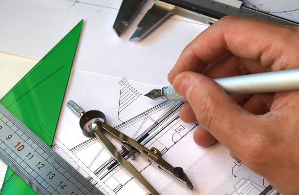 Architect working over blueprints, several drafting tools over the table
