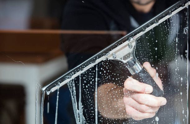 A soapy window with a squeegee cleaning the glass