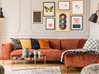 Eclectic living room interior with comfortable velvet corner sofa with pillows