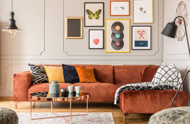 Eclectic living room interior with comfortable velvet corner sofa with pillows