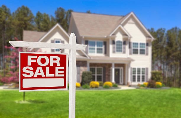 Home for sale real estate sign and beautiful new house.