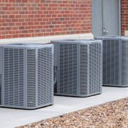 Horizontal shot of commercial air conditioners outside near a maintenance door.