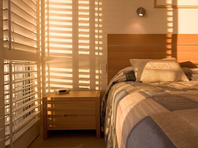 Beautiful golden light filtering through shutters in bedroom.
