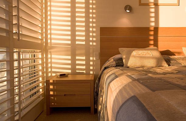 Beautiful golden light filtering through shutters in bedroom.
