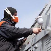 A commercial painter on the stairs spray painting a steel exteri