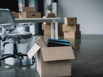 Cardboard box with folders and office supplies in floor during relocation