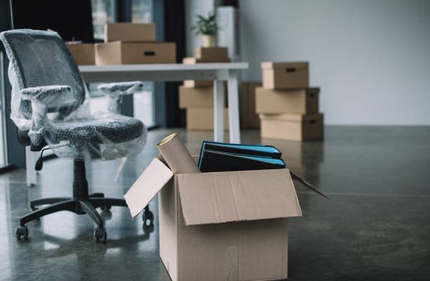 Cardboard box with folders and office supplies in floor during relocation