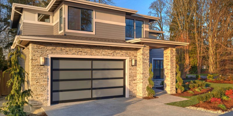 Modern contemporary house exterior with luxury details, landscaping, stone, wood, glass, lots of large windows.