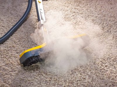 Using dry steam cleaner to sanitize floor carpet.