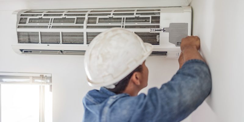 Air conditioner, ac repair and building hvac maintenance of a handyman and builder on home renovation. electric technician, service worker and contractor in a house for equipment installation on wall