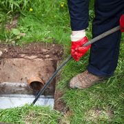 Drain being cleared by worker in navy overalls.