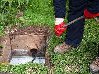 Drain being cleared by worker in navy overalls.