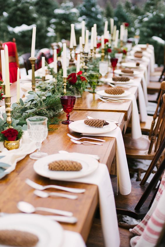 A-beautiful-winter-wedding-table-with-an-evergrene-runner-red-glasses-and-blooms-pinecones-and-white-porcelain