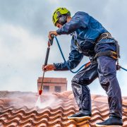 Worker washing the roof with pressurized water