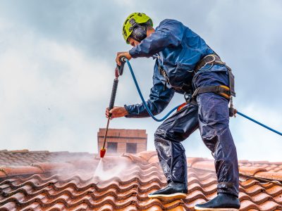 Worker washing the roof with pressurized water