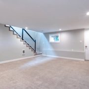 Light grey and spacious basement area with staircase.