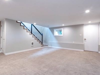Light grey and spacious basement area with staircase.