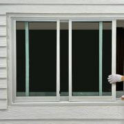 Construction worker repairing the sliding window on artificial woods siding.